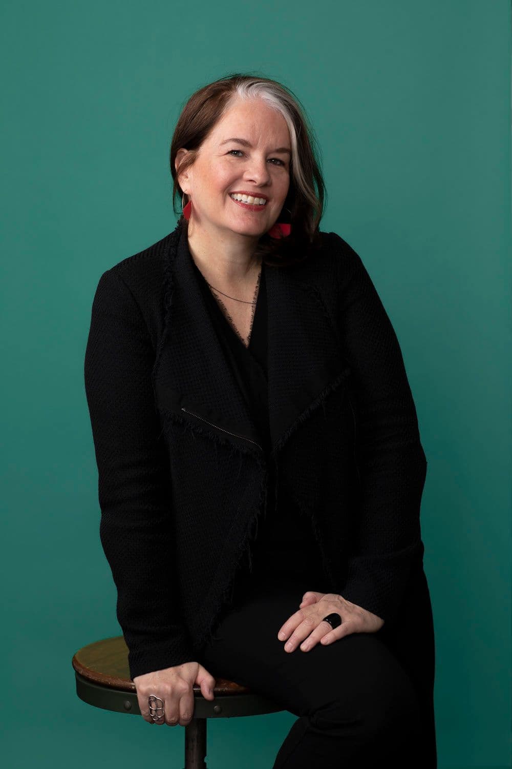 Kenna Kay sitting on a stool against a green backdrop.