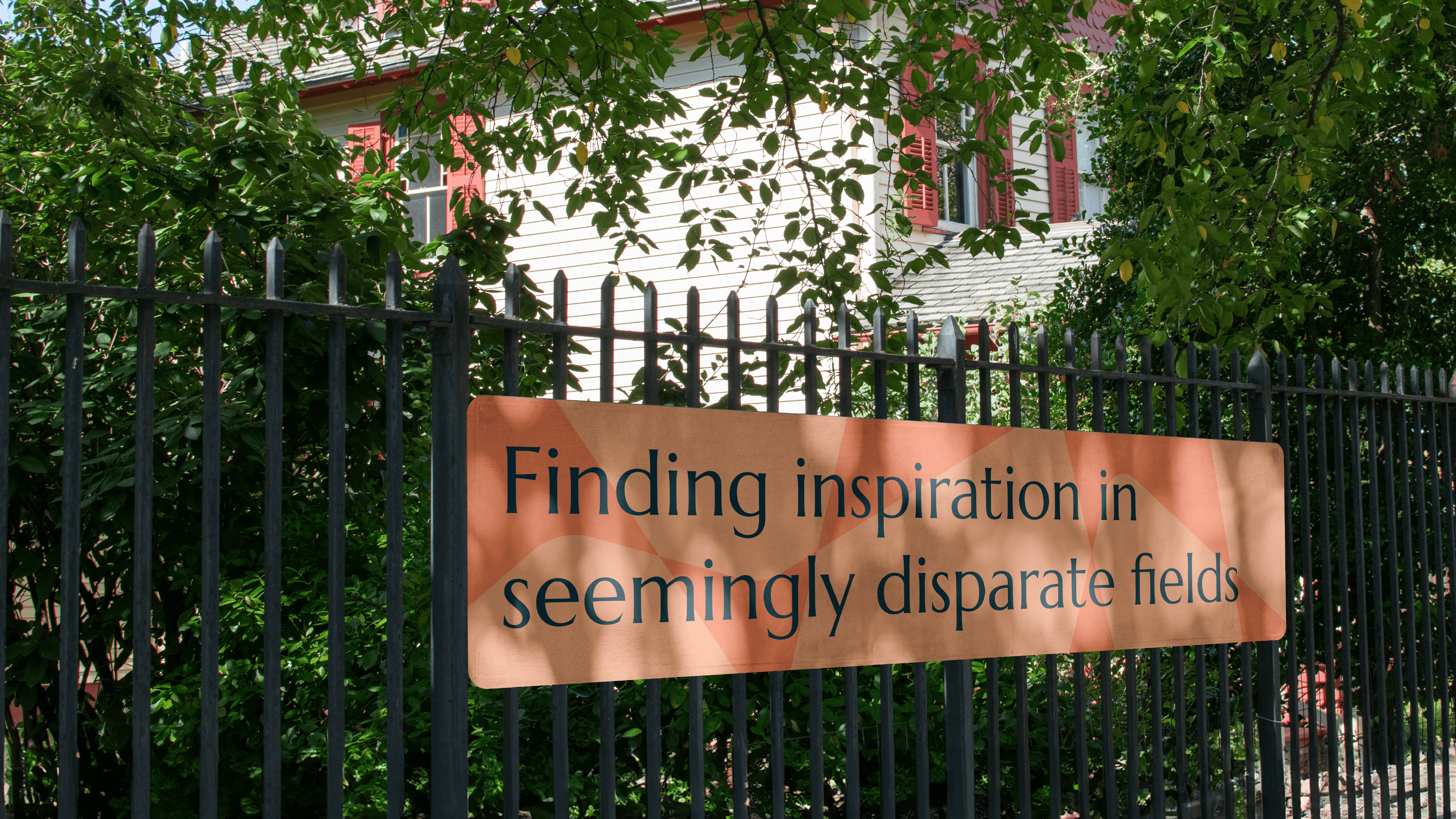 Orange banner reading 'Finding inspirations in seemingly disparate fields' against fence with Lewis Latimer house in the background behind trees.