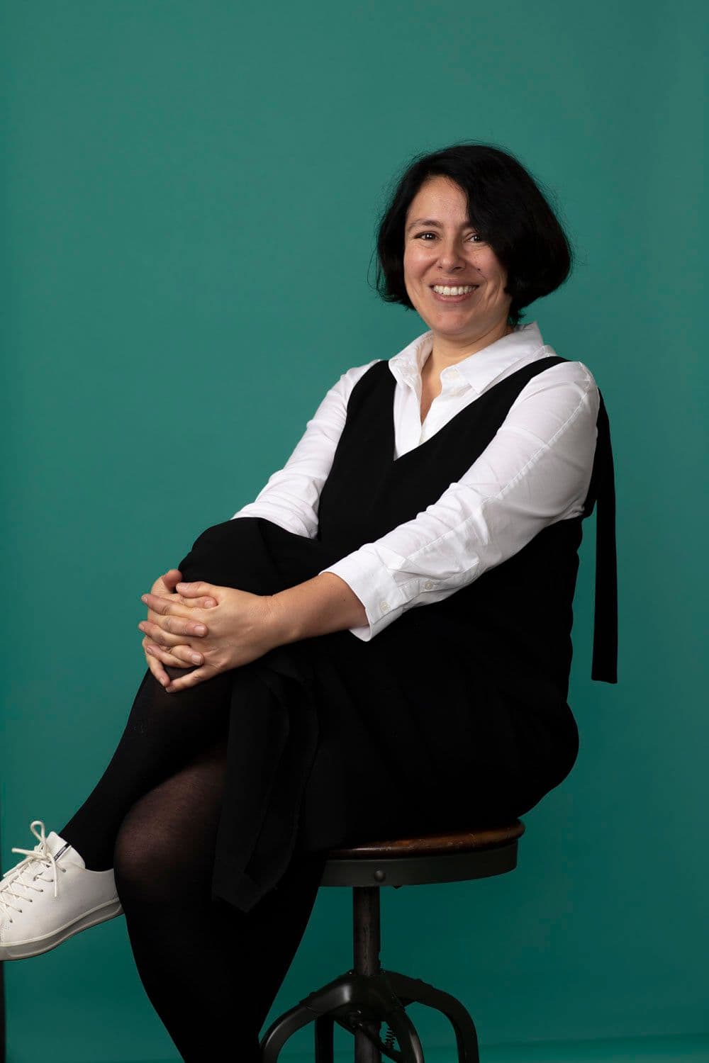 Sem Devillart sitting on a stool against a green backdrop.