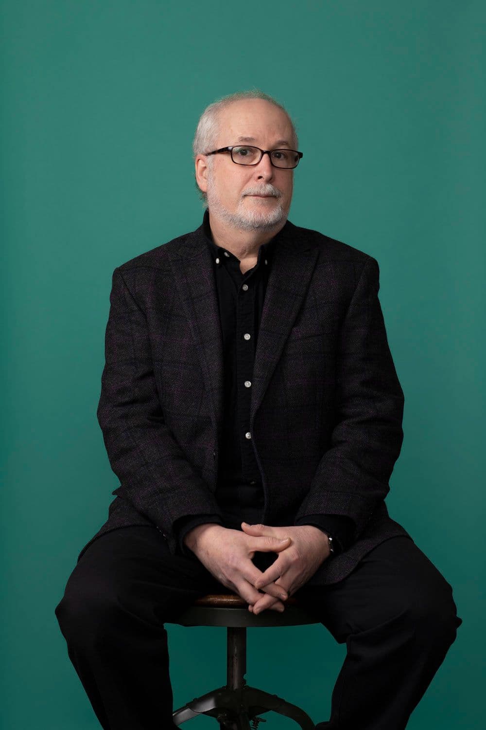 Scott Lerman sitting on a stool against a green backdrop.
