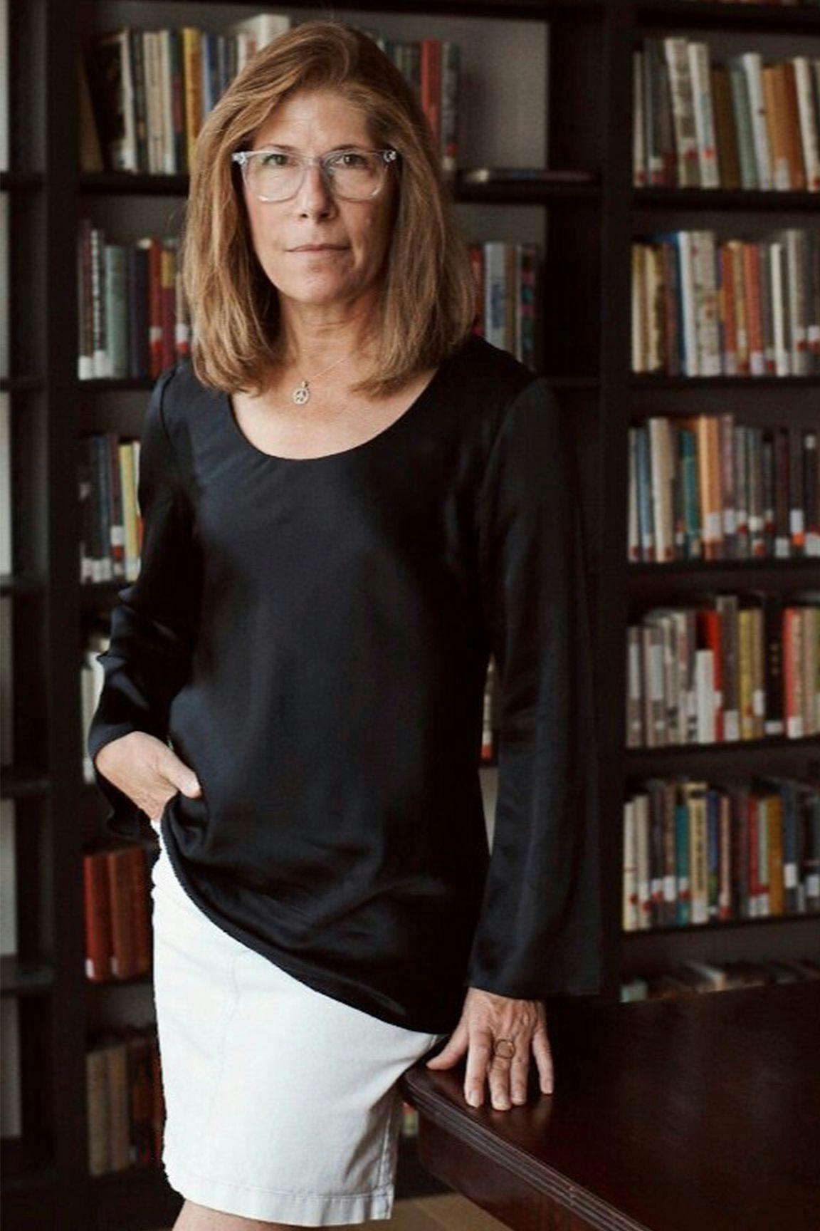 Elizabeth Talerman leaning against a table with bookshelves behind her.